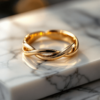 alliance pour femme en or avec un corps qui s'entrelace. posé sur du marbre blanc