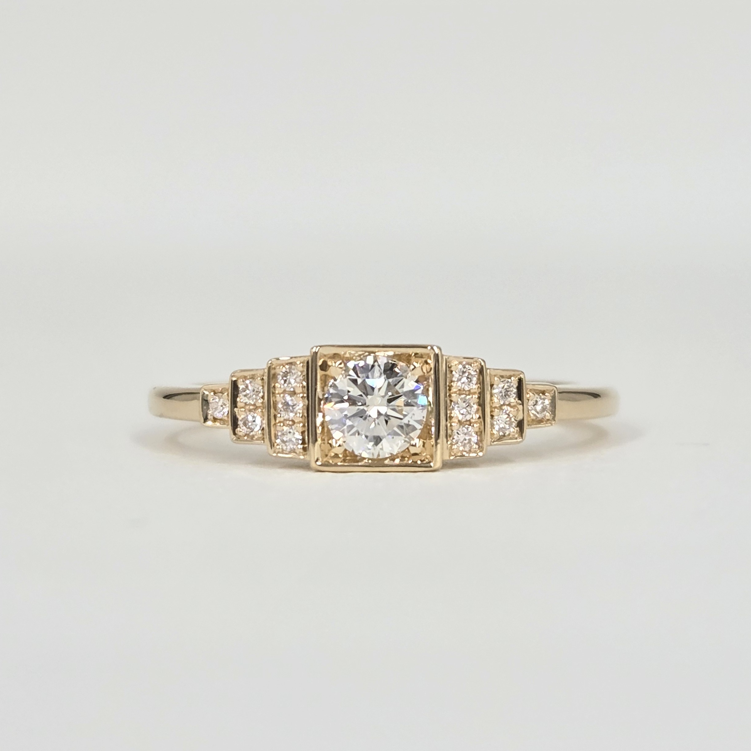 Bague en or jaune avec diamant central serti clos et pavage de diamants sur gradins