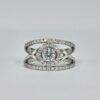Bague en or blanc croisé avec halo de diamants et diamant central rond serti 4 griffes.