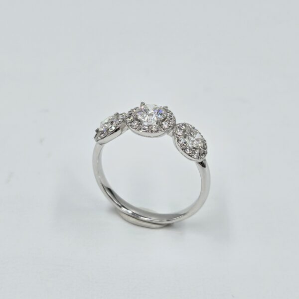 Bague trilogie en or blanc avec trois diamants ronds entourés de halos pavés