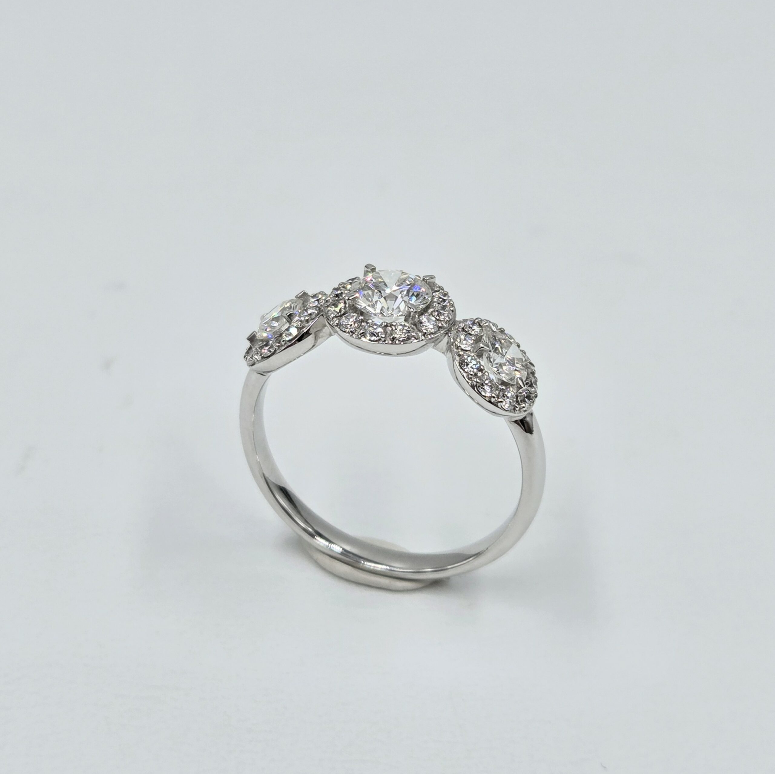 Bague trilogie en or blanc avec trois diamants ronds entourés de halos pavés