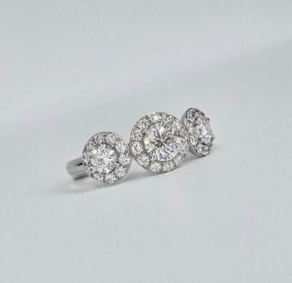 Bague trilogie en or blanc avec trois diamants ronds entourés de halos pavés