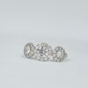 Bague trilogie en or blanc avec trois diamants ronds entourés de halos pavés.