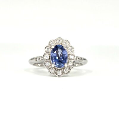 Bague marguerite en or blanc, saphir ovale bleu entouré de diamants ronds.