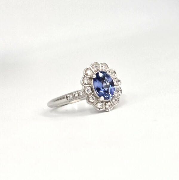Bague marguerite en or blanc, saphir ovale bleu entouré de diamants ronds.