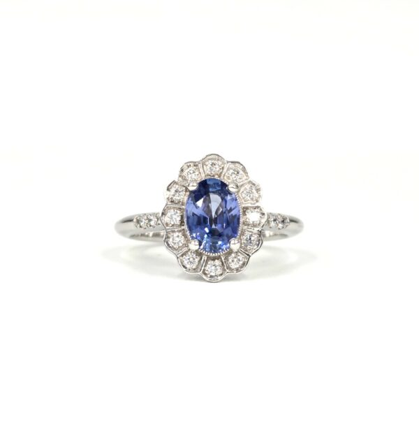 Bague marguerite en or blanc, saphir ovale bleu entouré de diamants ronds.