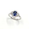 Bague en or blanc avec saphir ovale et halo de diamants en double courbe.