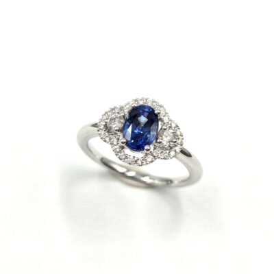 Bague en or blanc avec saphir ovale et halo de diamants en double courbe.