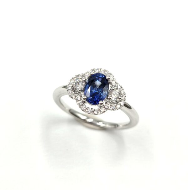 Bague en or blanc avec saphir ovale et halo de diamants en double courbe.