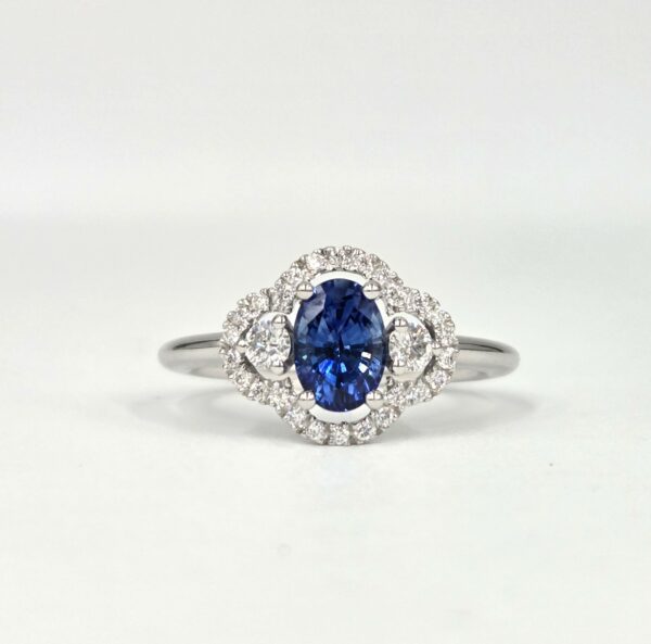 Bague en or blanc avec saphir ovale et halo de diamants en double courbe.