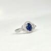 Bague en or blanc avec saphir ovale et halo de diamants en double courbe.