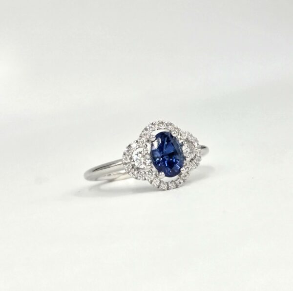 Bague en or blanc avec saphir ovale et halo de diamants en double courbe.