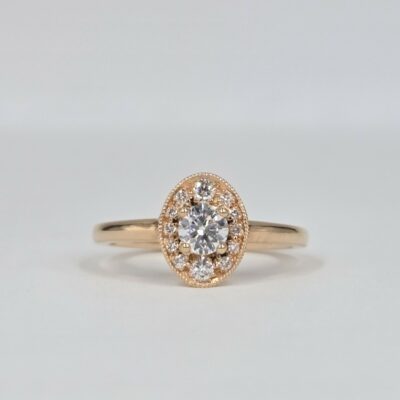 bague en or rose avec diamant rond central et halo ovale pavé de diamants