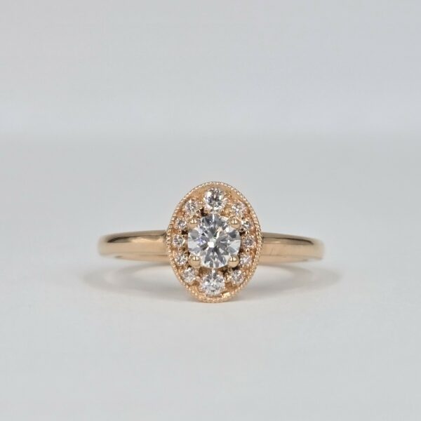 bague en or rose avec diamant rond central et halo ovale pavé de diamants