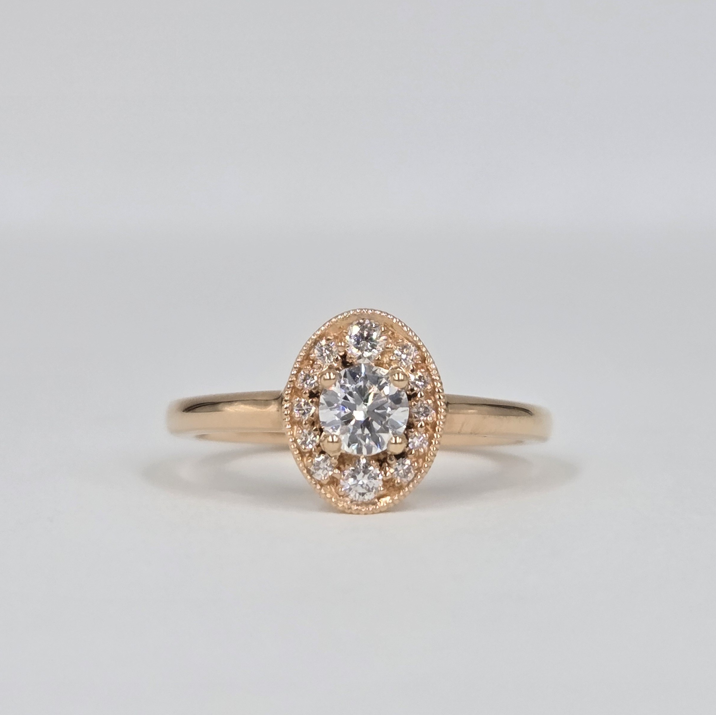 bague en or rose avec diamant rond central et halo ovale pavé de diamants
