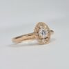 bague en or rose avec diamant rond central et halo ovale pavé de diamants