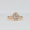 bague en or rose avec diamant rond central et halo ovale pavé de diamants