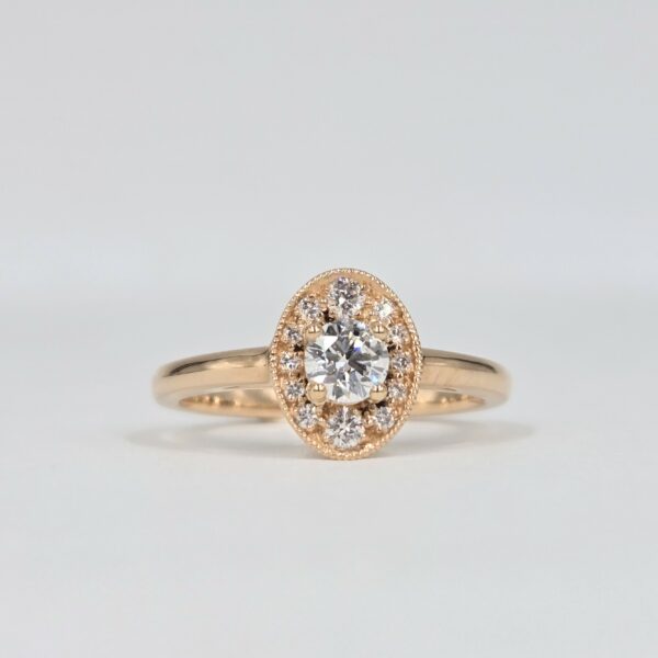 bague en or rose avec diamant rond central et halo ovale pavé de diamants