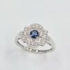 Bague en or blanc palladié avec saphir bleu rond et pavage de diamants en forme art déco.