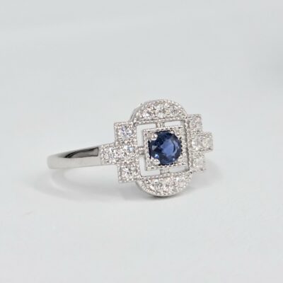 Bague en or blanc palladié avec saphir bleu rond et pavage de diamants en forme art déco