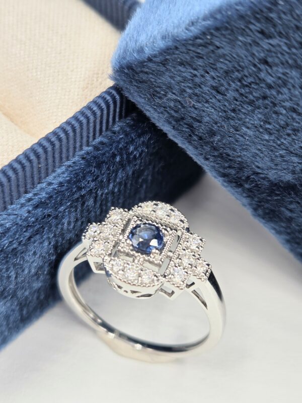 Bague en or blanc palladié avec saphir bleu rond et pavage de diamants en forme art déco